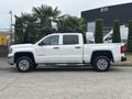 A 2016 GMC Sierra 1500 pickup truck in white with chrome wheels and a crew cab design