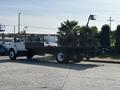 A white 2018 Ford F-750 flatbed truck with a black flatbed and a mesh stake bed is parked in a lot
