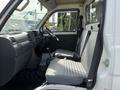 Interior of a 2010 Daihatsu Hijet showing two gray patterned seats a dashboard and gear shift in the front cabin