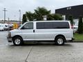 A silver 2021 Chevrolet Express van is parked with windows on the sides and a rear hatch door visible