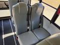 Two gray bus seats with seatbelts installed in a row inside a vehicle designed for passenger transport