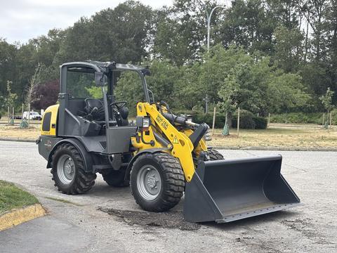 A yellow and black 2014 Wacker Neuson WL34 compact wheel loader with a large front bucket in the foreground