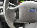 Close-up of a Ford steering wheel featuring controls for cruise control and a Ford logo on a leather surface