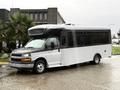 A 2019 Chevrolet Express bus with a white and black exterior parked on a wet surface