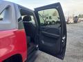 A red 2011 Chevrolet Avalanche with the back door open showcasing the interior seats and door trim