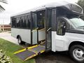 A 2020 Chevrolet Express bus with its doors open and a deployable wheelchair ramp extended