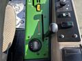 Close-up of the control panel of a 2021 John Deere 1575 featuring levers buttons and a gauge with a green and black color scheme