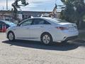 A white 2015 Hyundai Sonata parked on a street with an angled view showing its side and rear features including sleek lines and a modern design