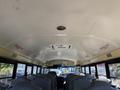 The interior of a 2013 International CE300 school bus featuring blue plastic seats and a white ceiling with ventilation and warning signs