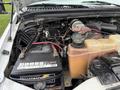 Close-up view of the engine compartment of a 2000 Ford F-450 showing the battery coolant reservoir and various engine components and wiring