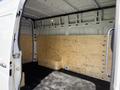 A 2022 Mercedes-Benz Sprinter van with an empty wooden interior featuring plain walls and a wooden bench along the back