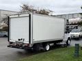 A 2019 Ford Econoline box truck with a white exterior parked at an angle showing the rear and side view with black trim and white wheels