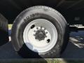 Close-up of a black and white tire mounted on a 2012 Freightliner M2 106 truck showcasing the tread and wheel design