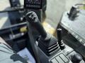 A close-up of the control lever and dashboard of a 2022 Caterpillar 306 excavator showing various buttons and displays