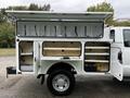A 2015 Ford F-350 SD with an open service body featuring multiple storage compartments and shelves for tools and equipment