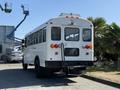 A white 2013 International CE300 school bus with a rectangular rear window and multiple red and amber lights on the back