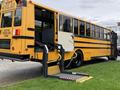 A 2014 Freightliner B2 school bus with a lowered wheelchair lift at the entrance and an open door for accessibility