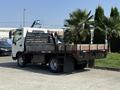 A 2012 Hino 155 truck with a flatbed and wooden side rails parked on a concrete surface