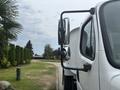 A 2006 Freightliner M2 106 truck showing close-up of its side mirror and cab with a white exterior color