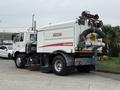 A 2009 UD Trucks UD 3300 street sweeper with a white body and red accents featuring a rear-mounted broom and elevated warning lights
