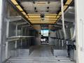 A 2012 Ford Econoline interior displaying metal shelving on both sides and a spacious floor area leading to the driver's seat at the front