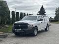 A 2016 RAM 1500 pickup truck in white with a black front grille and a cap on the truck bed