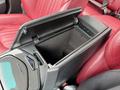 A black center console with an open lid in a 2016 Maserati Ghibli featuring leather upholstery in a deep red color