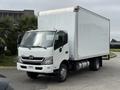 A 2018 Hino 195 box truck with a white cargo area and a grey cab is parked with its front slightly angled towards the viewer