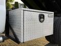 A diamond plate toolbox mounted on the side of a white 2006 Ford F-550 with a lock and handle visible on the front