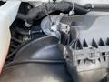 Close-up of the engine compartment of a 2023 GMC Savana showing various components including an air intake and hose connections