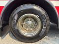 A close-up of a chrome wheel rim and tire of a 1999 Freightliner FL80 showcasing the tire tread and rim design