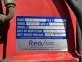 A blue label on a red surface displaying vehicle information including make model unit serial and inspection dates