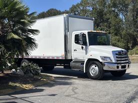 A white 2020 Hino 338 box truck with a large cargo area and a silver front grille parked on a paved surface