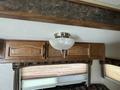 A ceiling light fixture with a frosted glass bowl design and a chrome finish mounted on a wooden cabinet