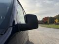 Close-up of the side mirror of a dark blue 2013 Ford E-350 Super Duty van with a sleek design and a smooth finish