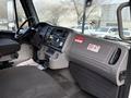Interior view of a 2015 Freightliner M2 featuring a driver’s seat control panel with buttons and dials on the dashboard