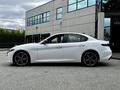 A white 2023 Alfa Romeo Giulia with sleek lines and distinctive circular alloy wheels is shown from the side view