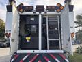 The rear view of a 2012 International DuraStar 4300 featuring open doors revealing equipment and machinery with a ladder attached