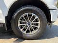A close-up of a silver alloy wheel with a six-spoke design on a 2018 Ford F-150 featuring a rugged tire tread pattern