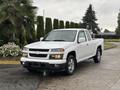 A 2011 Chevrolet Colorado pickup truck in white with a sleek design and chrome accents parked on a paved surface
