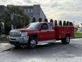 A red 2013 Chevrolet Silverado 3500HD truck with a utility bed parked on the street