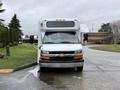 A 2013 Chevrolet Express van in white with a black front grille and headlights parked on a paved surface