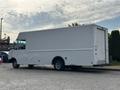 A 2018 Ford Econoline van with a white exterior and cargo space in the back parked on a street