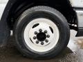 A close-up of a wheel from a 2009 Ford Econoline featuring a white steel rim with multiple lug nut openings and a black tire with visible tread patterns