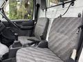 Two front seats of a 2008 Suzuki Carry with grey patterned upholstery and a gear shift in between them