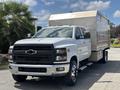 A white 2020 Chevrolet Silverado with a large silver trailer attached is parked at an angle showcasing its front view and prominent grille
