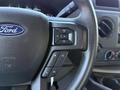 Close-up of the steering wheel of a 2021 Ford Econoline showing the Ford logo and controls for volume and media functions