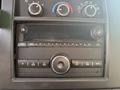 Dashboard control panel of a 2021 Chevrolet Express featuring knobs for temperature and four speaker buttons with a central media player and various navigation buttons