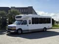 A 2017 Chevrolet Express shuttle bus with a white exterior and gray accents featuring large windows and a high roof design