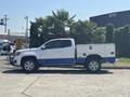 A white 2017 Chevrolet Colorado truck with a blue trim and a service bed parked with palm plants visible above the cab